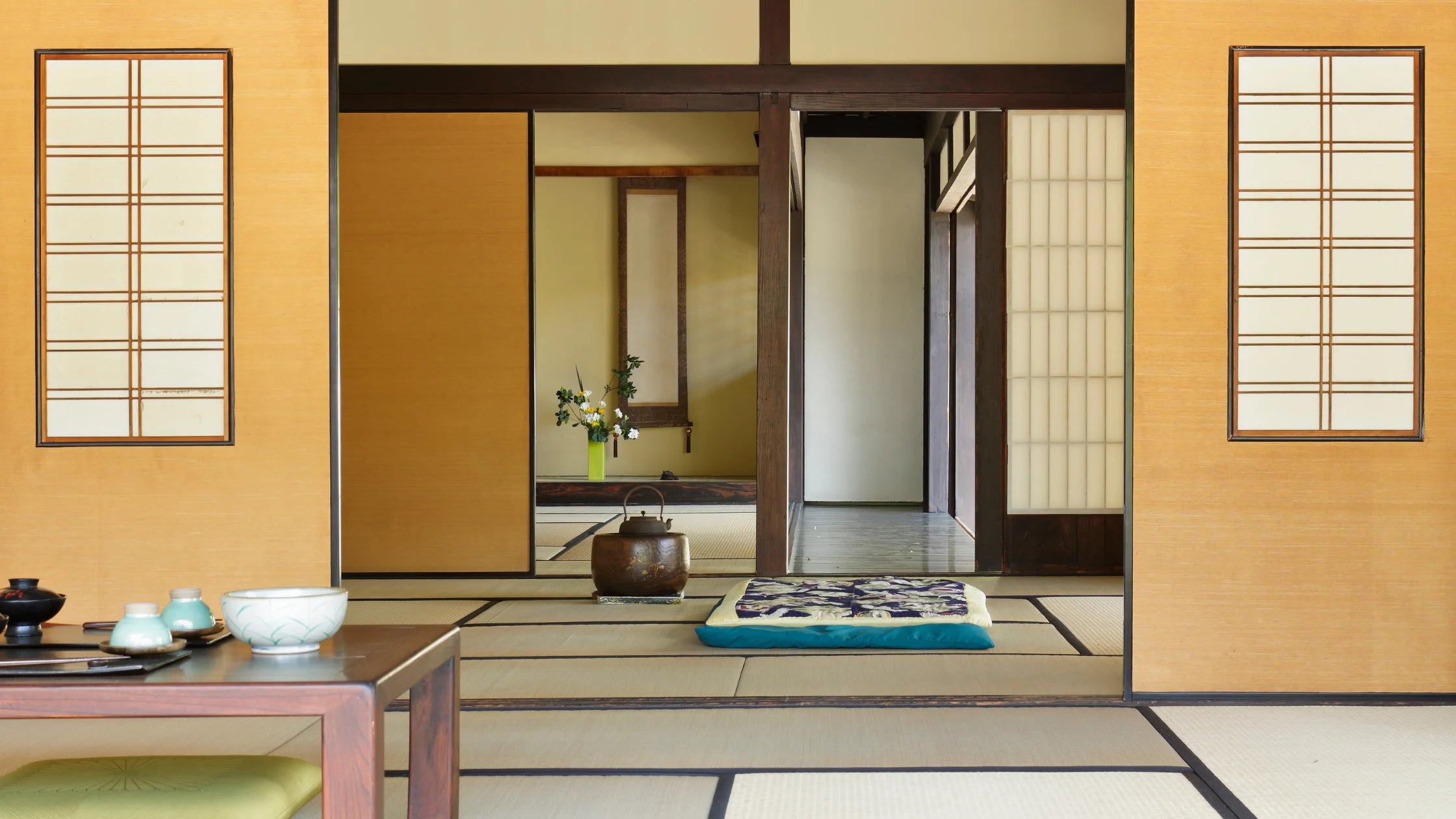 Traditional Japanese interior with wooden walls, tatami mat flooring, and tea ceremony setup.