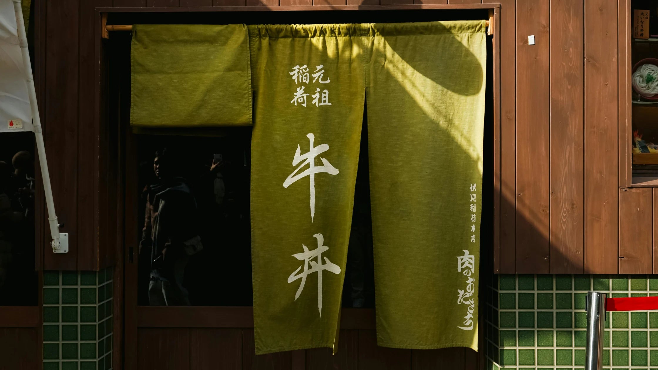 Green restaurant curtain with white text in a Japanese restaurant setting
