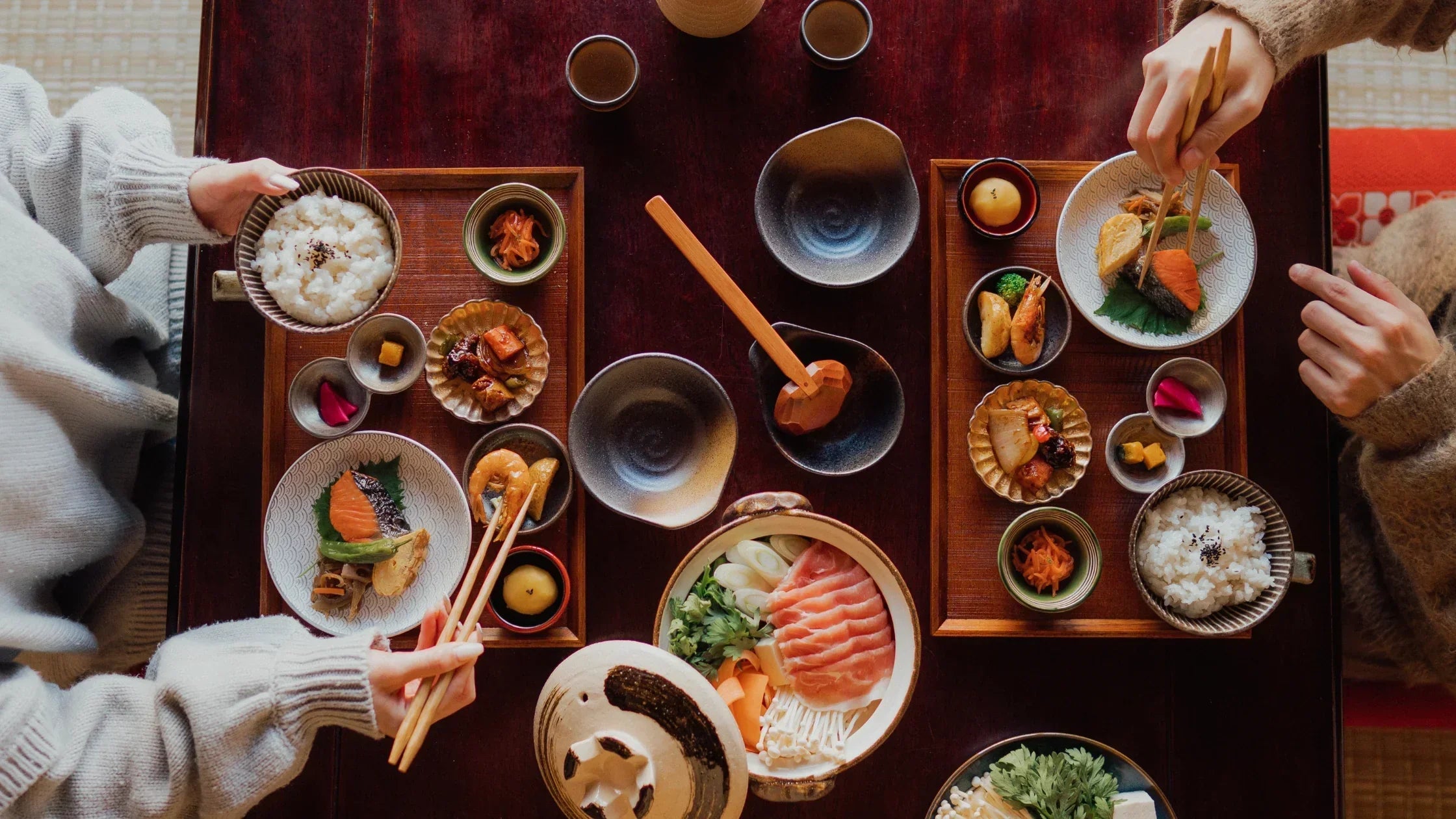 Japanese-style dinner party with guests enjoying traditional cuisine on tatami mats in a cozy, authentic setting.