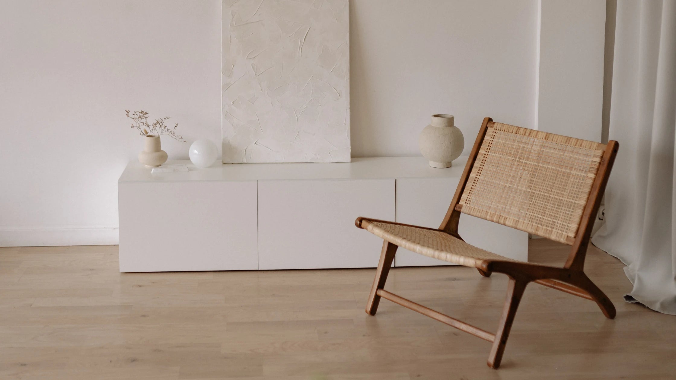 Wicker chair in a minimalistic room with white walls and wooden floor.