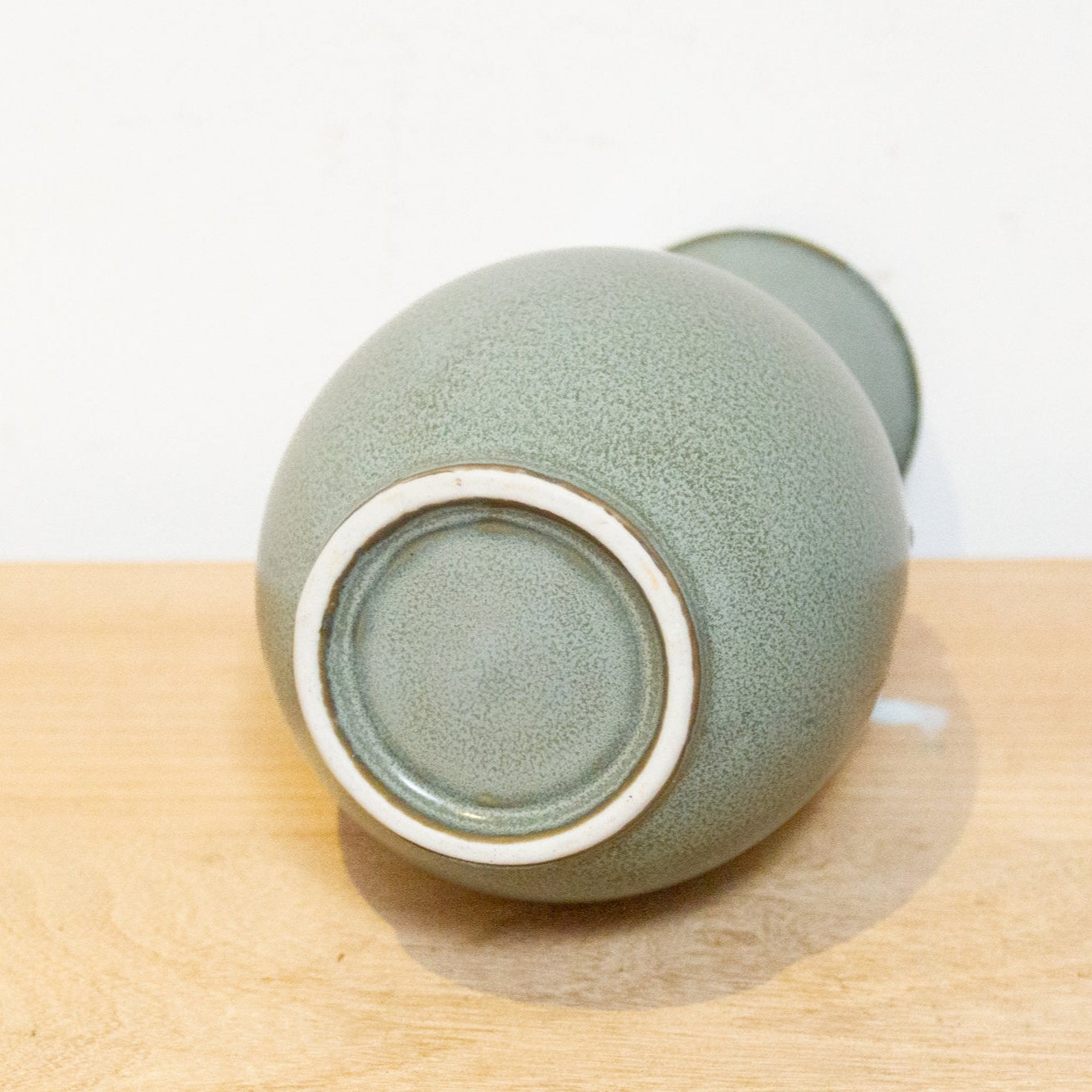 Green ceramic cup on a wooden surface with a white background