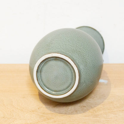 Green ceramic cup on a wooden surface with a white background